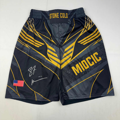 Autographed/Signed Stipe Miocic Black and Gold UFC MMA Trunks Shorts Ultimate Fighting Beckett BAS COA
